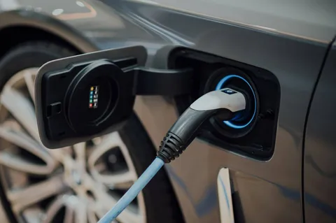 Connecteur de recharge branché sur une voiture électrique avec halo bleu électrique autour du port
